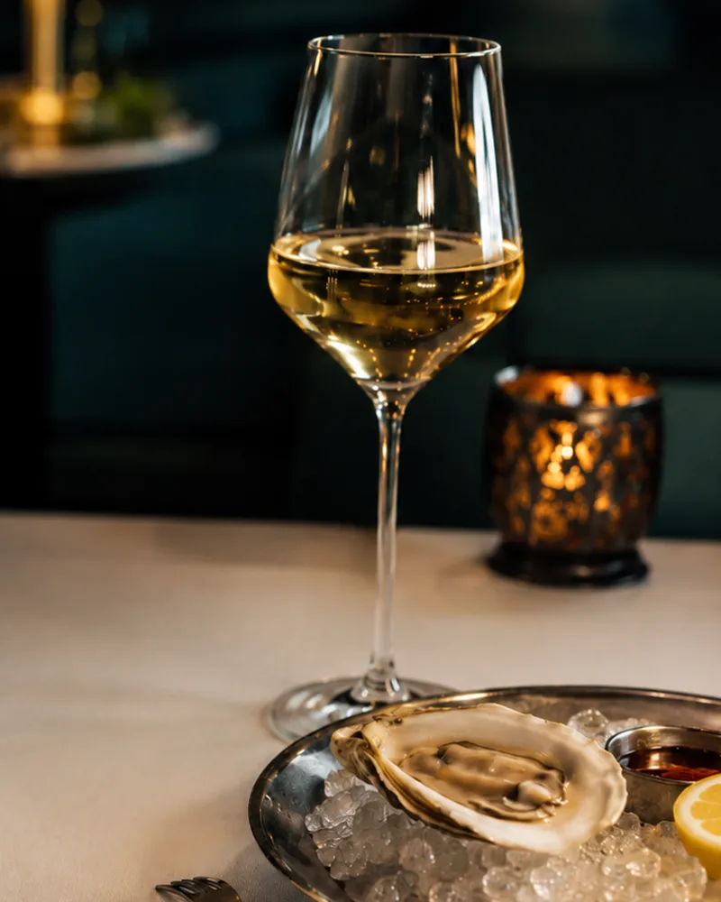 Glass of white wine and a fresh oyster on ice at Nautilus